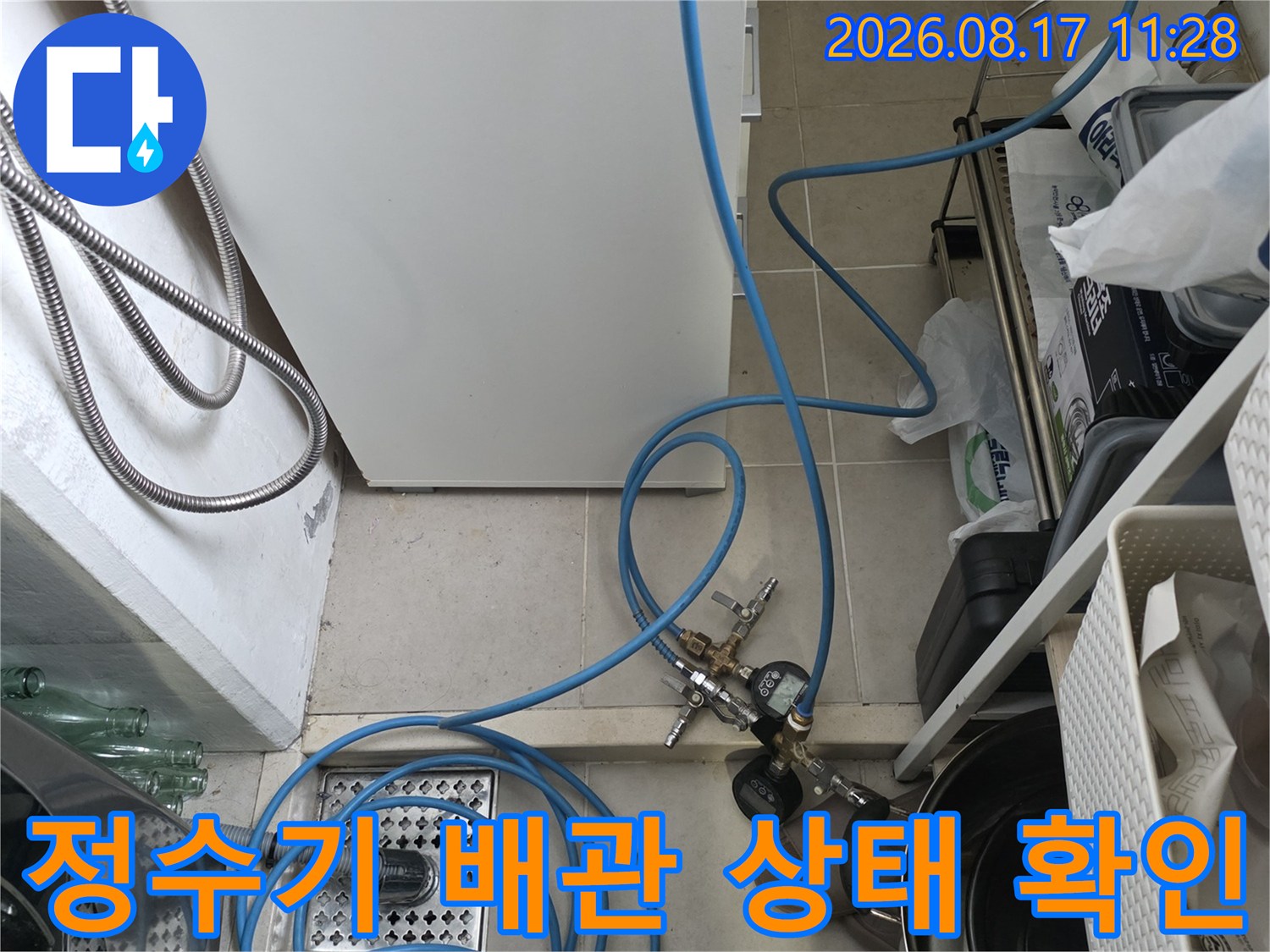 싱크대 하단 배수구와 연결된 파란색 정수기 호스 및 장비