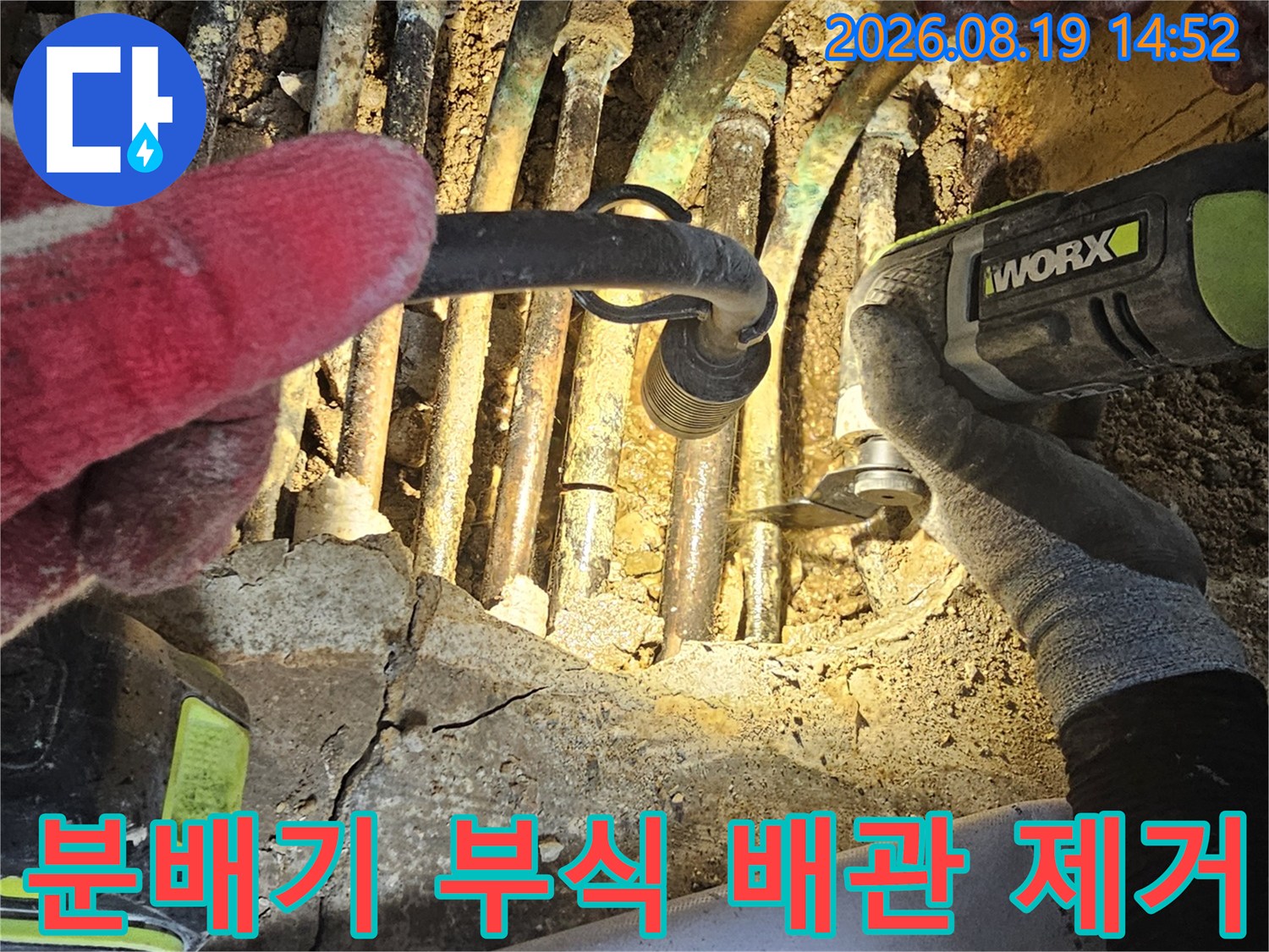 금속제 난방 분배기의 - 낡고 부식된 연결 부위를 전동 공구로 작업하는 장면