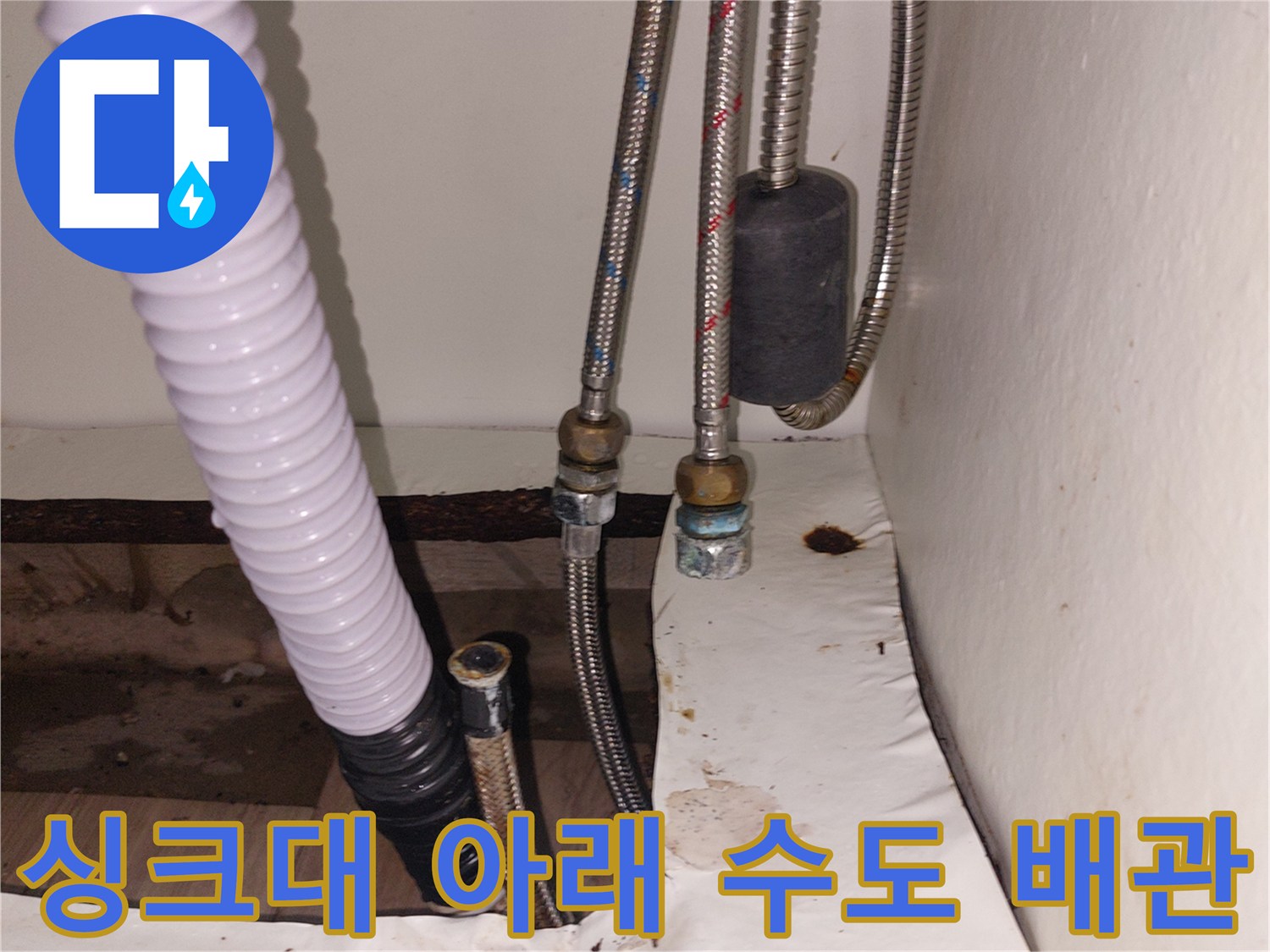 누수가 발생한 싱크대 하부의 금속 호스와 흰색 플라스틱 관
