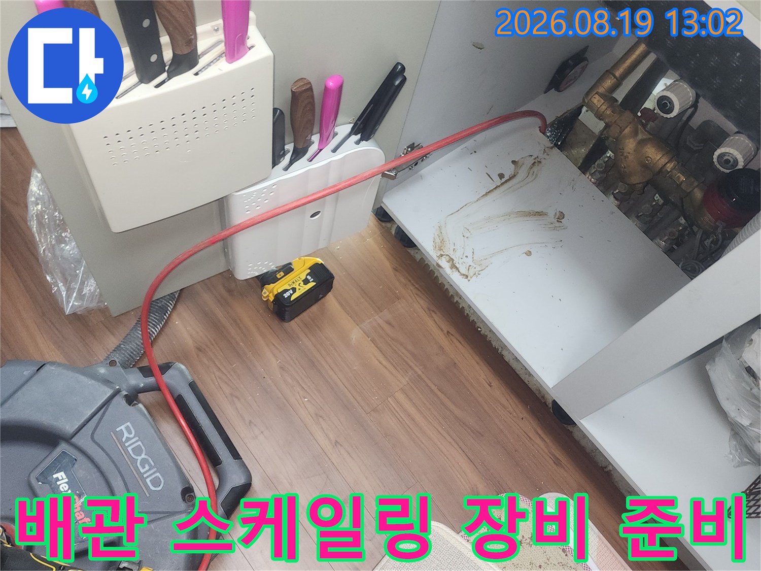 플렉스 샤프트 케이블이 연결된 리지드 배관 세척 장비와 싱크대 하부 모습