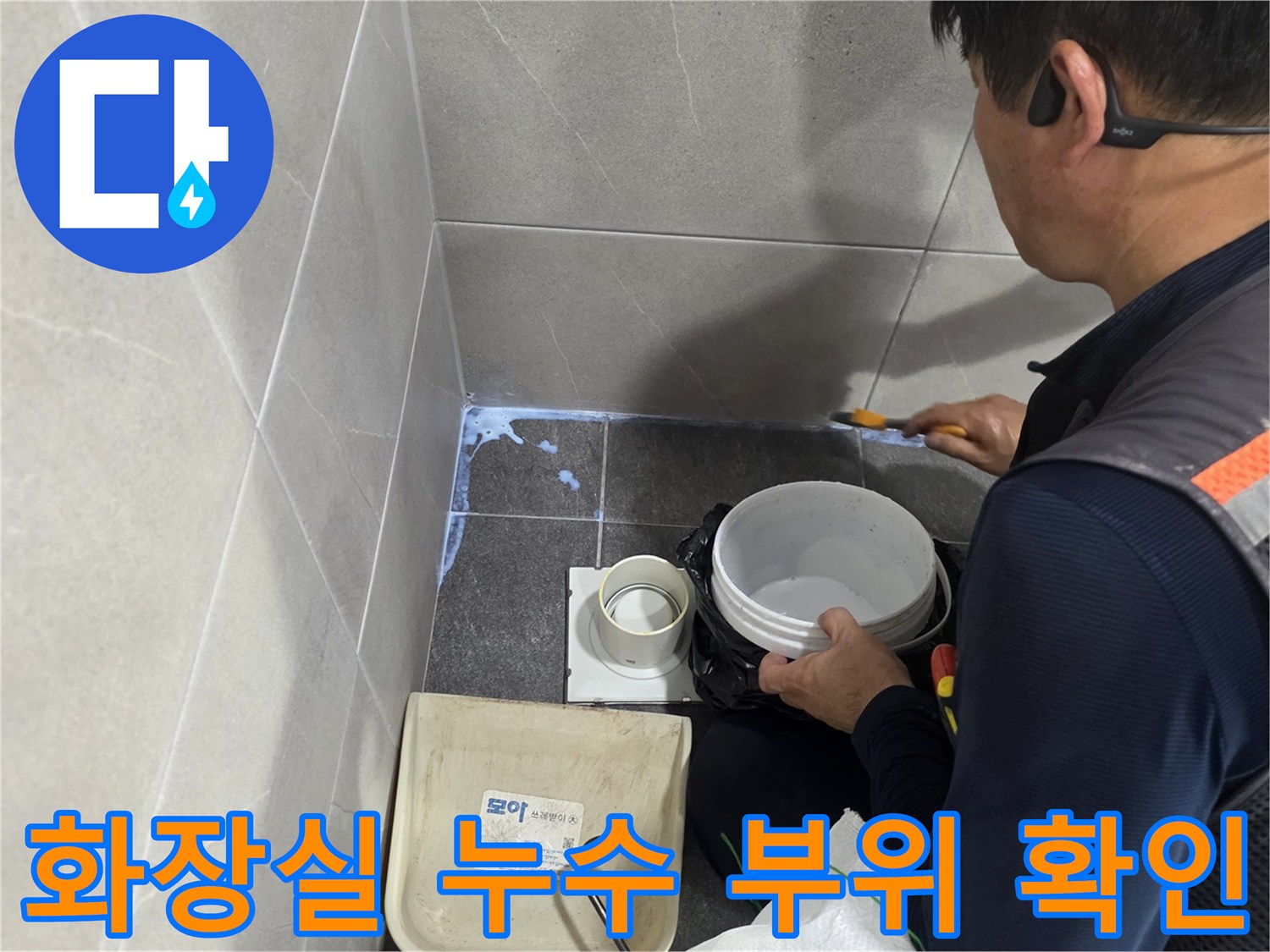 욕실 바닥 배수구 주변의 습기 찬 타일과 작업 도구들
