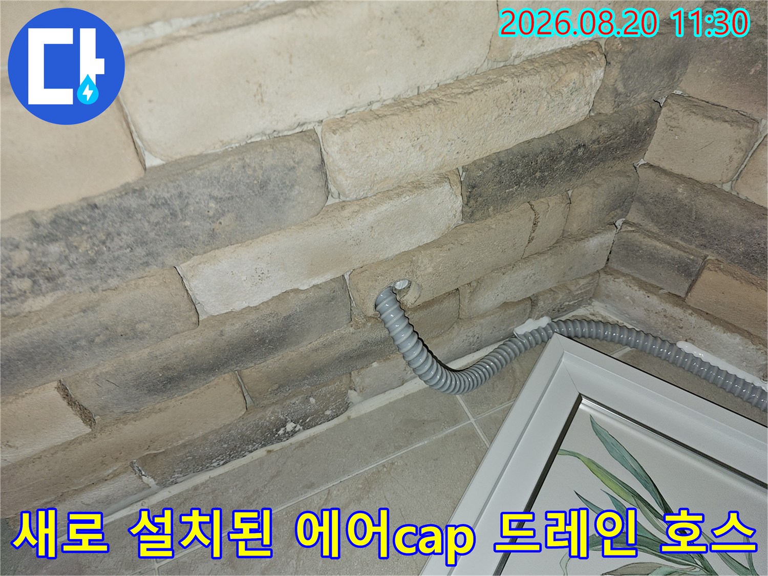 벽면 석재 마감 부위에서 외부로 뻗어 나온 회색 주름관
