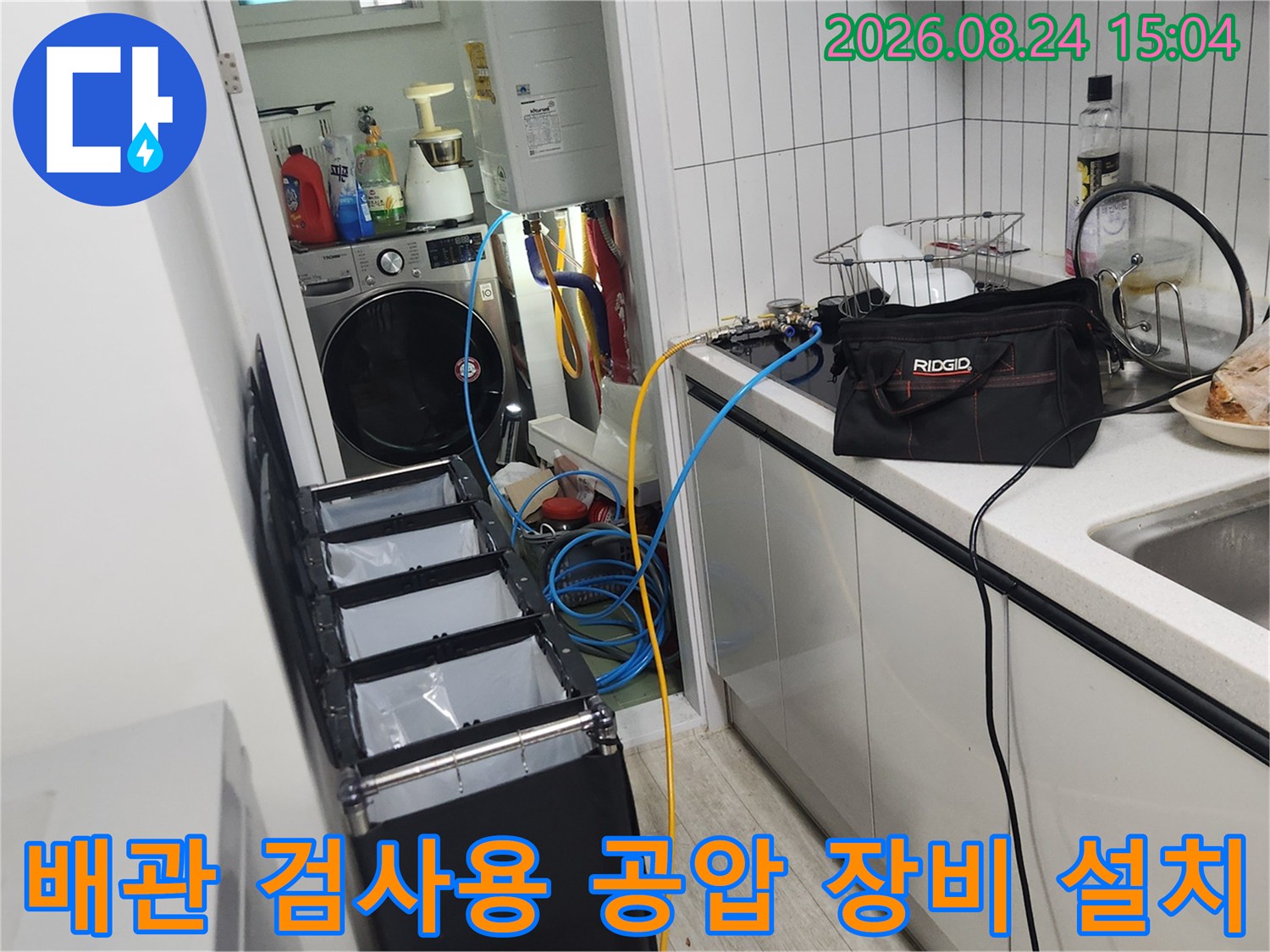 싱크대 옆 좁은 공간에 세팅된 배관 압력 측정용 호스와 장비
