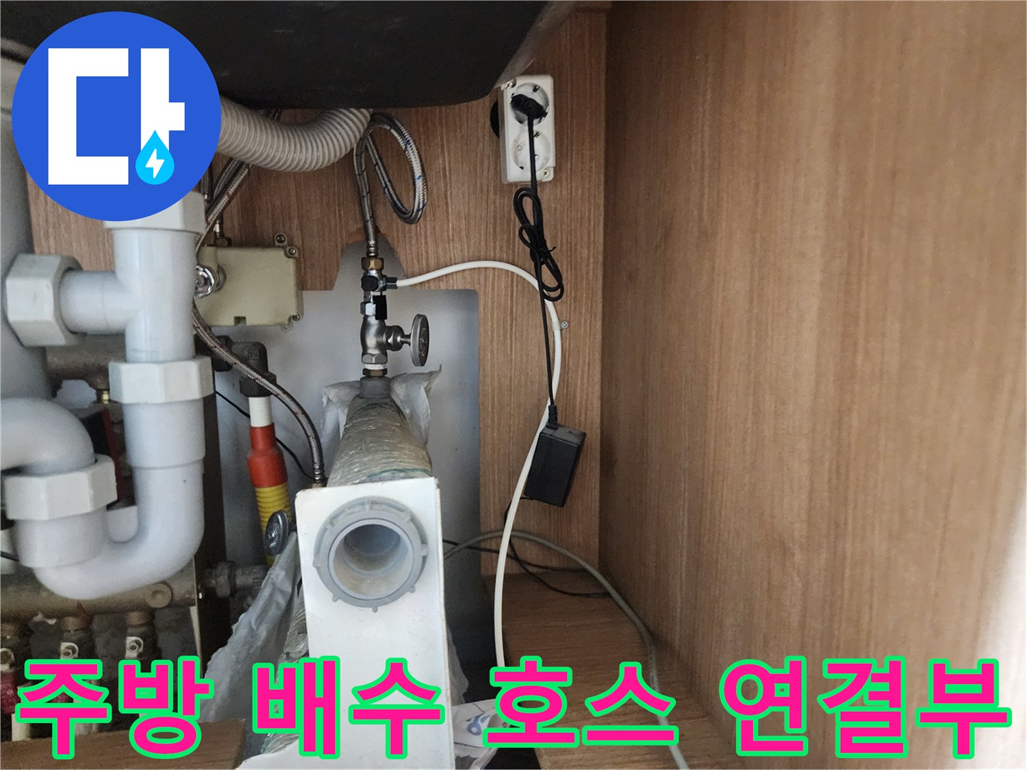 싱크대 하부장 내부의 굴곡진 배수 호스와 플라스틱 배관 구조