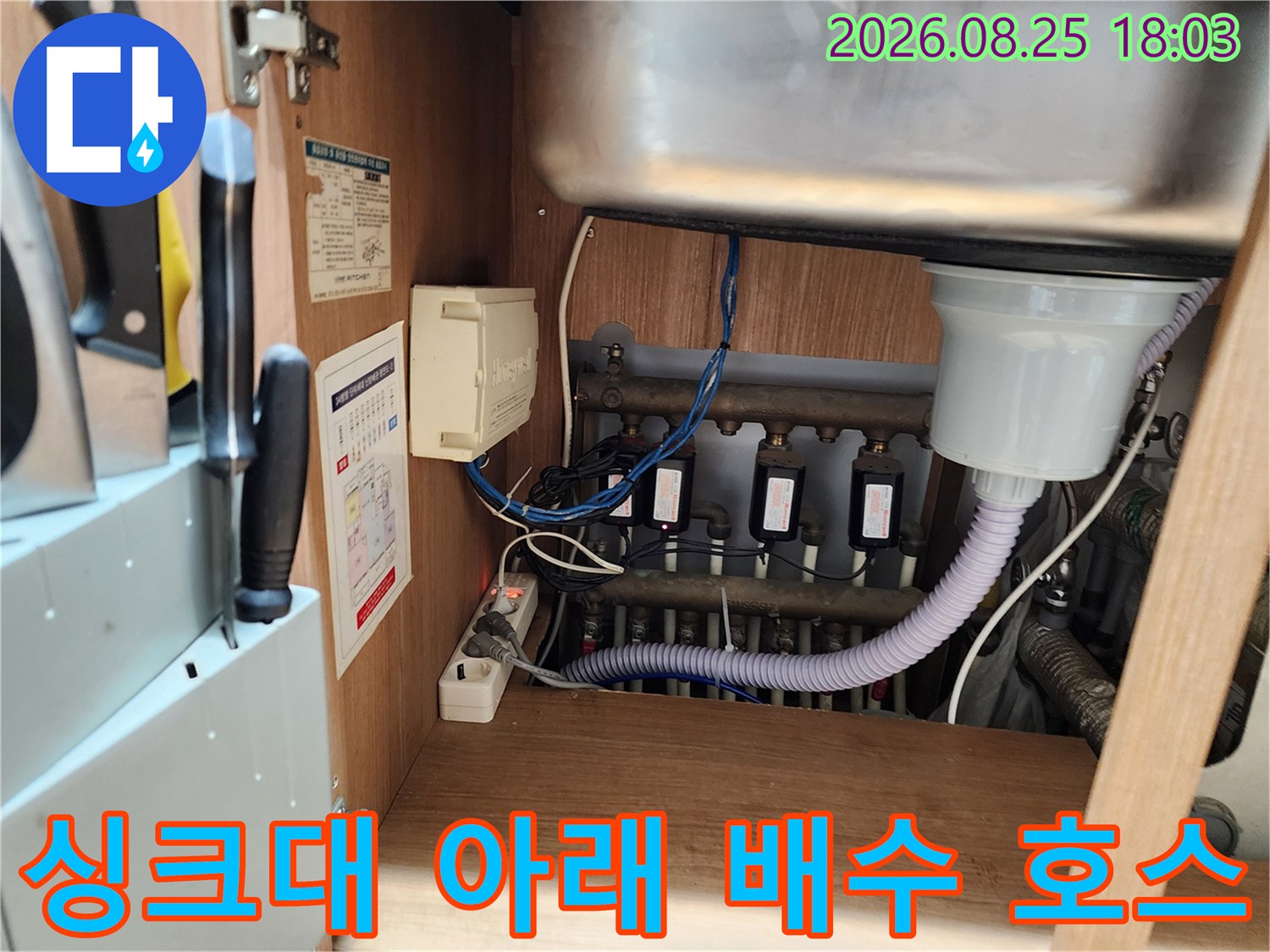 싱크대 하부장의 복잡한 배수 관로 및 연결 부위 모습