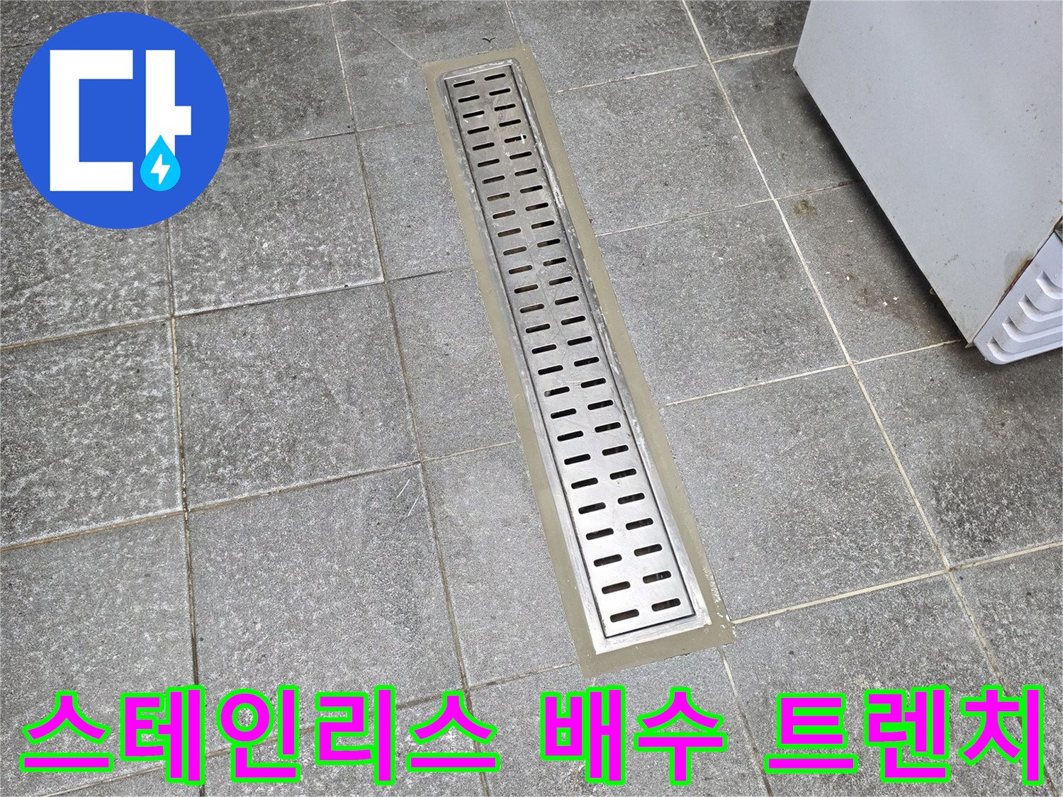 스테인리스 재질의 긴 배수 트렌치와 주변 바닥 타일