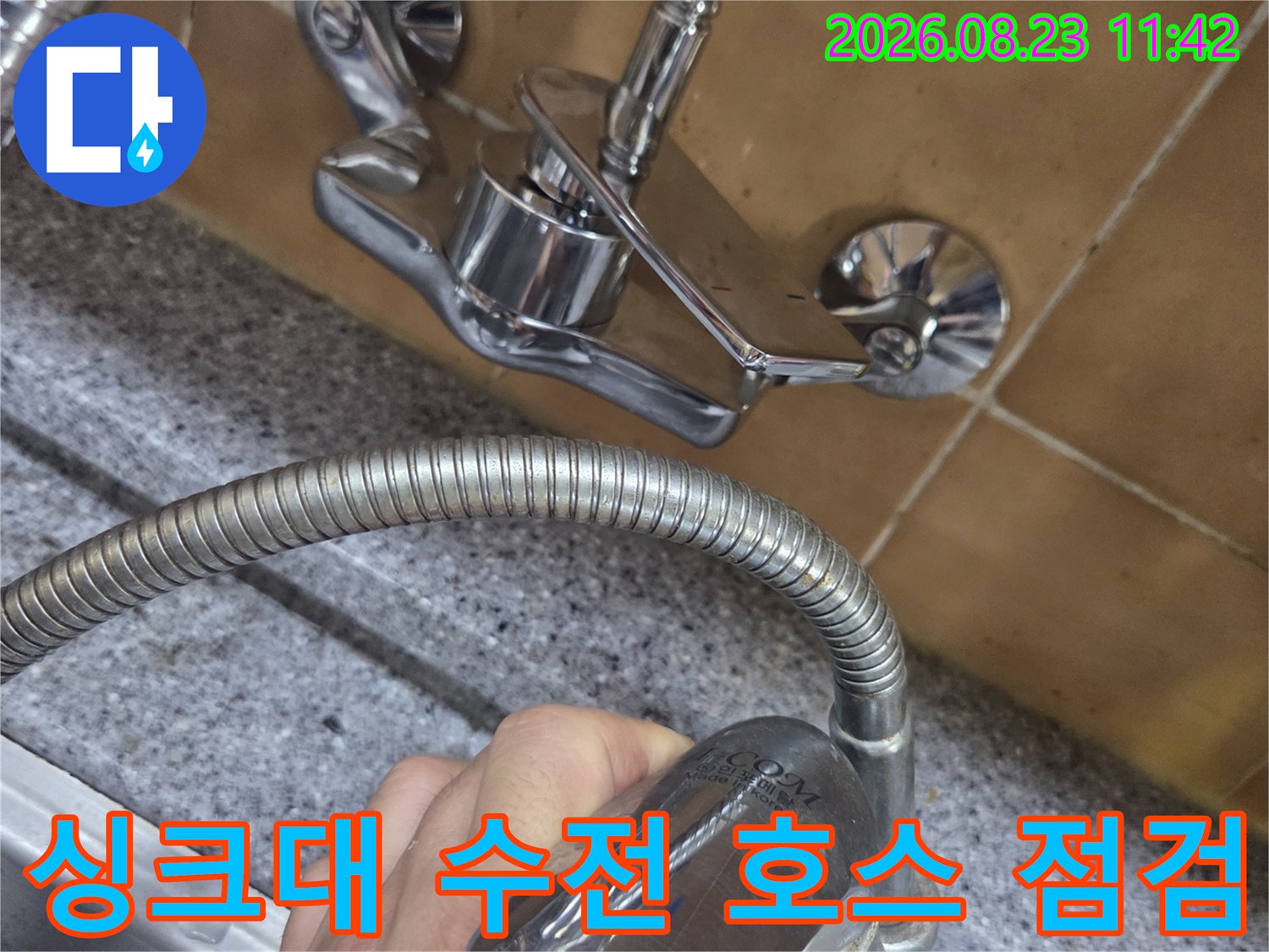 손으로 잡고 있는 싱크대 수전 헤드와 연결된 금속 호스 상세 사진