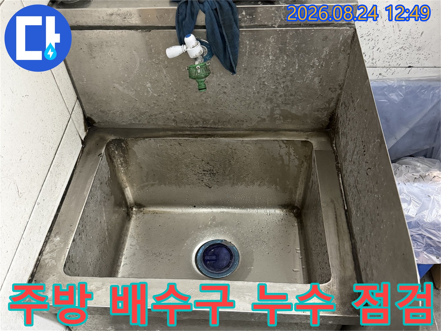 식당 싱크대 내부의 스테인리스 배수 구멍과 주변 배관 연결 상태입니다.