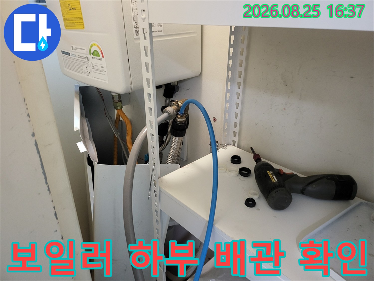 보일러 밑에 연결된 배관과 측정 장비가 설치된 현장 사진입니다.