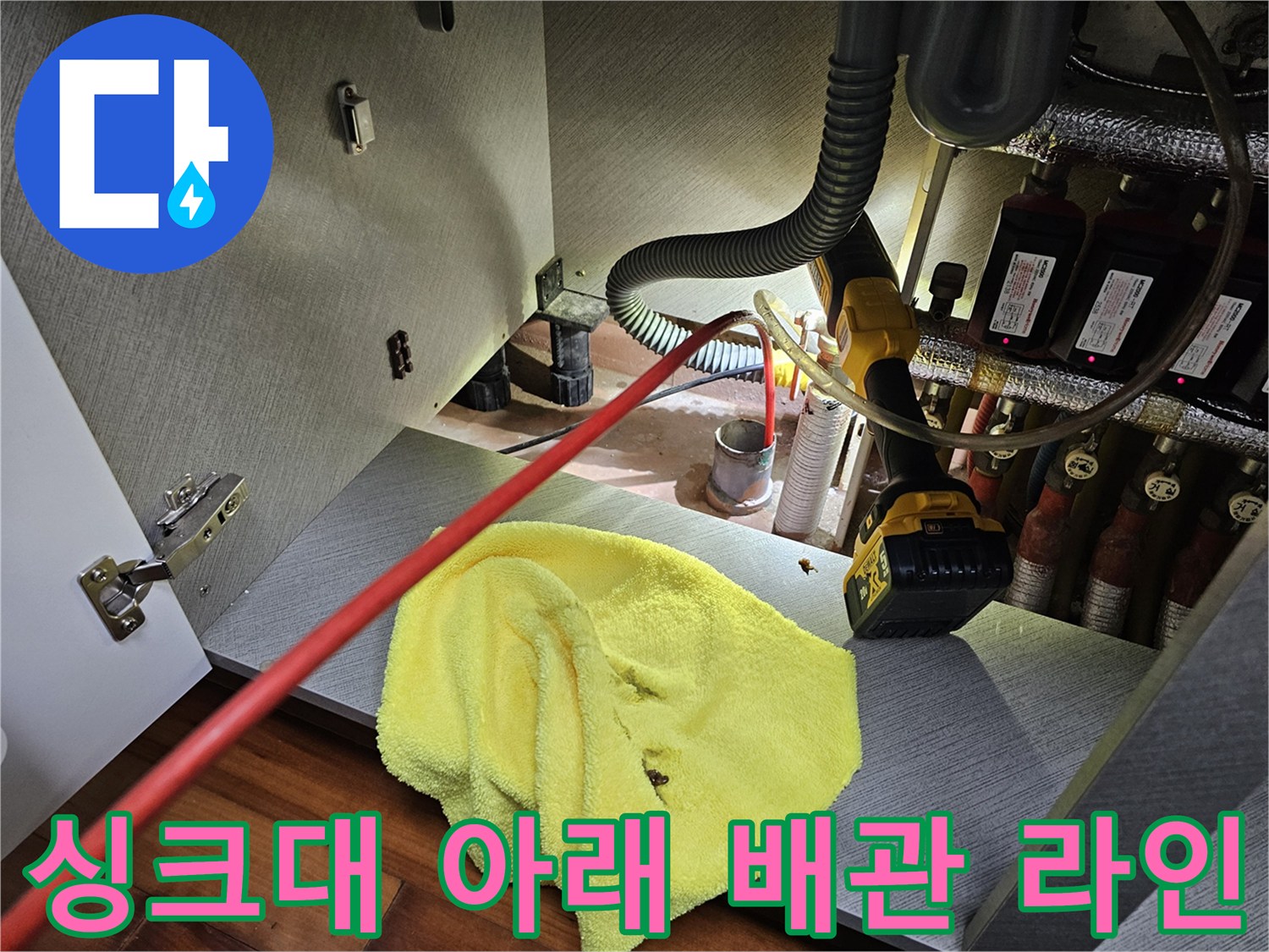 싱크대 밑 분배기와 연결된 여러 종류의 급수 및 온수 배관 모습입니다.