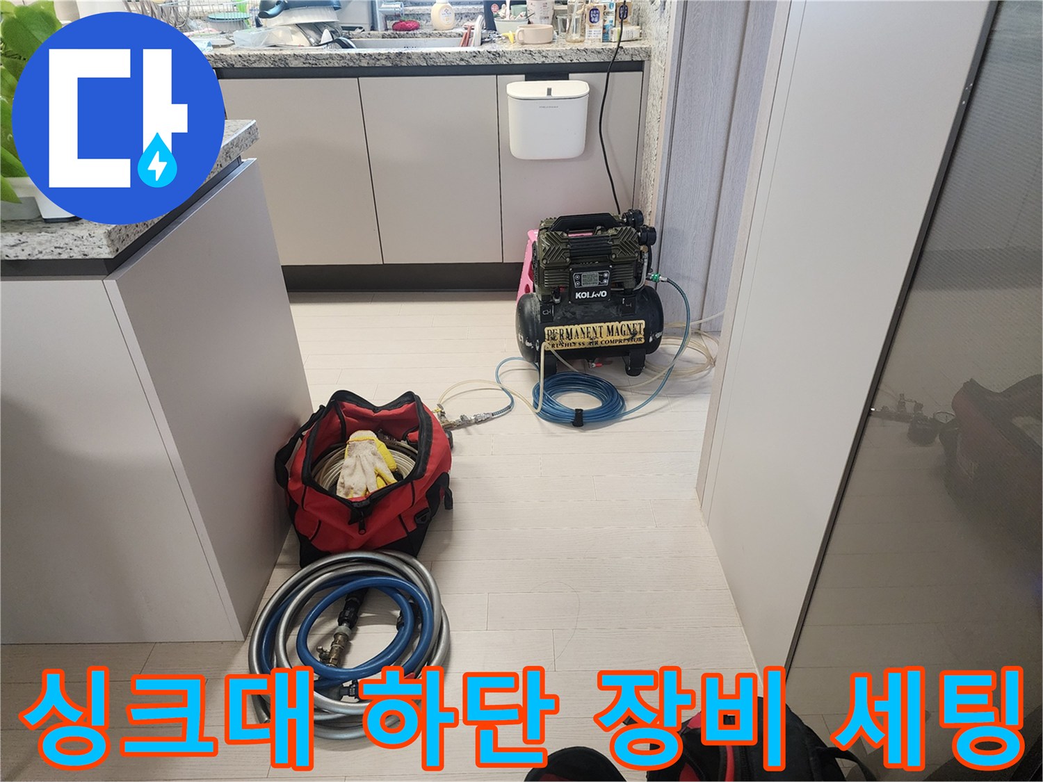 주방 싱크대 아래에 놓인 공압 테스트용 콤프레샤와 배관 점검 호스