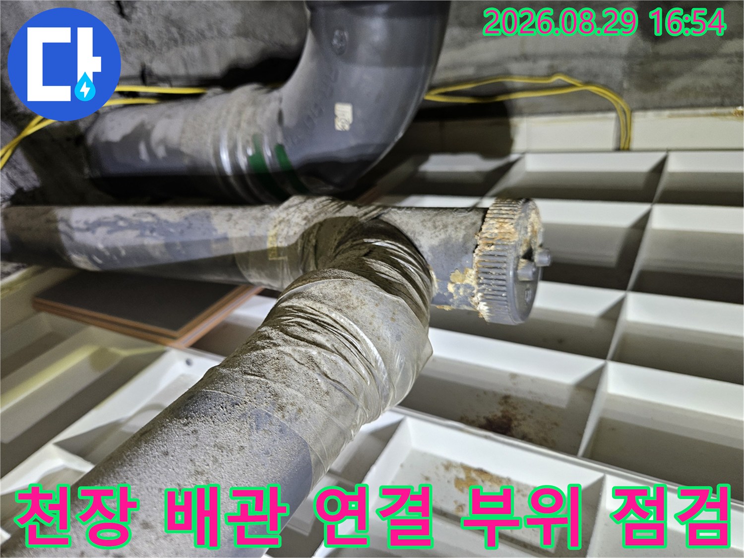 천장 내부에 노출된 배관의 연결 지점과 주변 습기 상태를 보여주는 모습입니다.