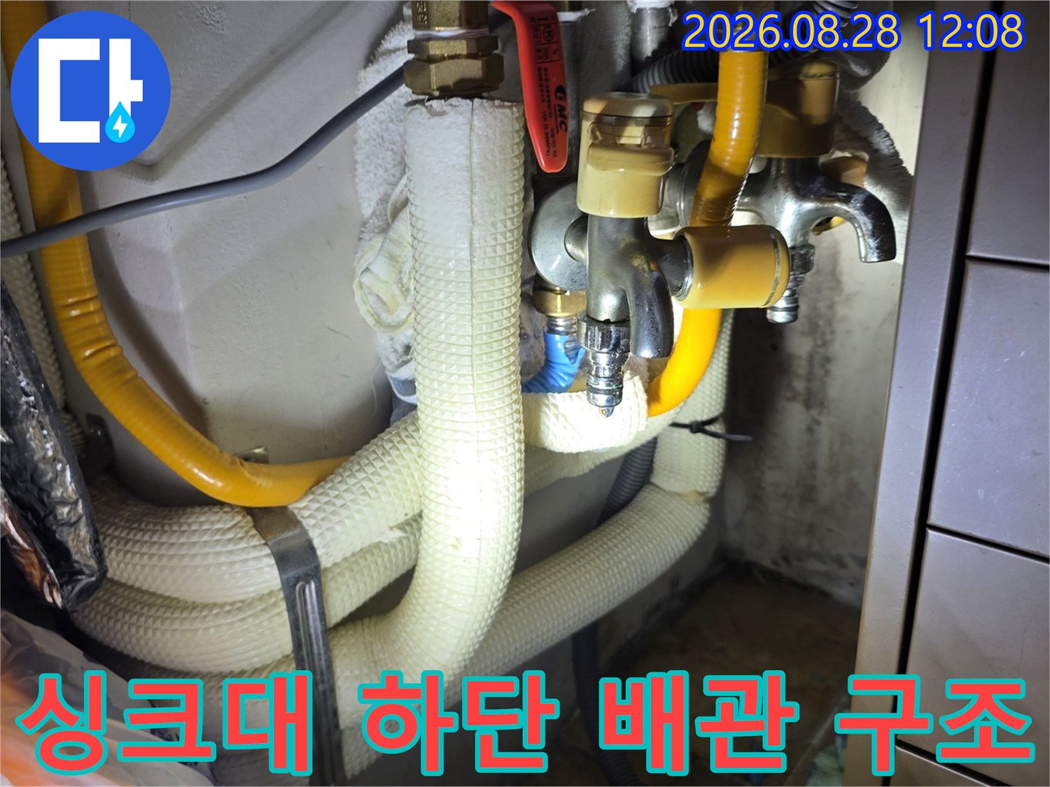 노란색 보온재와 금속 밸브가 있는 싱크대 아래쪽 배관 사진