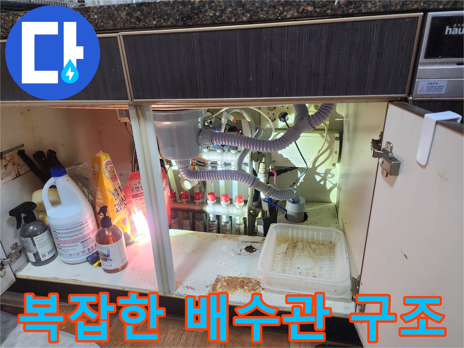 싱크대 밑에 연결된 여러 갈래의 하얀색 배수 호스와 분기 밸브들