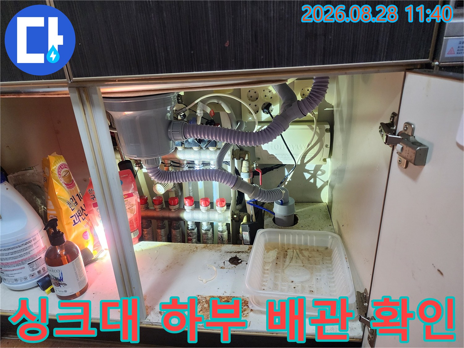 싱크대 아래쪽의 정수 필터 장치와 굴곡진 배관들의 모습