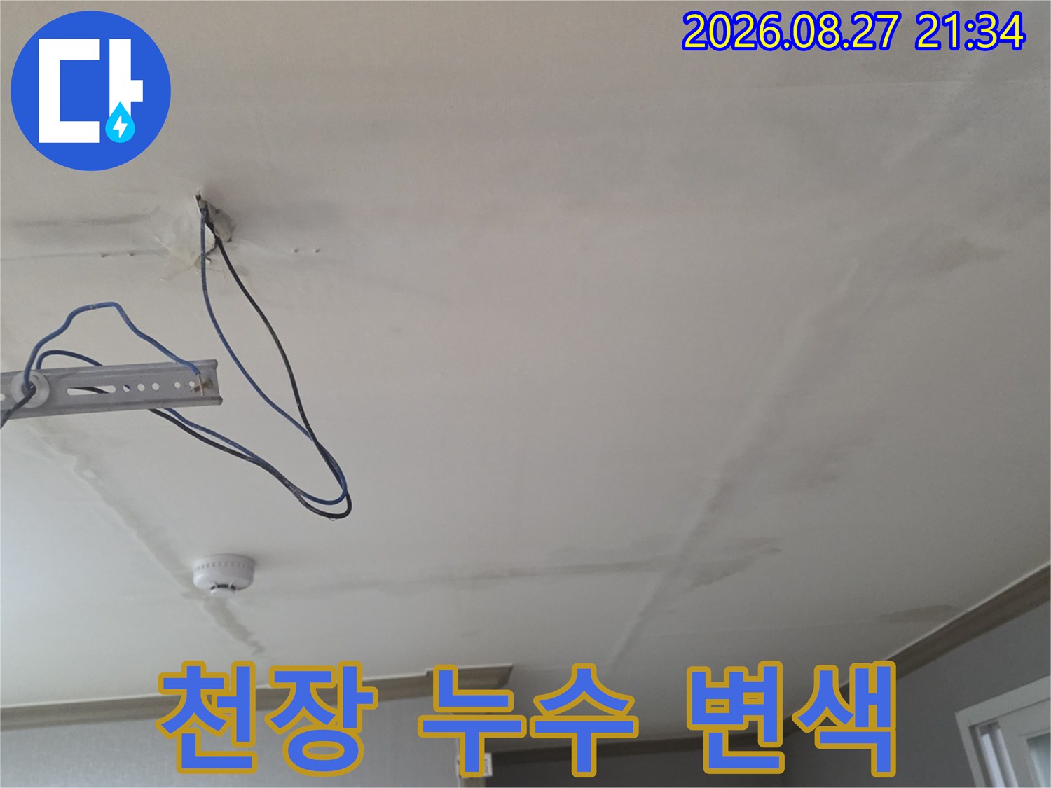 천장 도배지의 누수 흔적과 노출된 배선 및 구조물