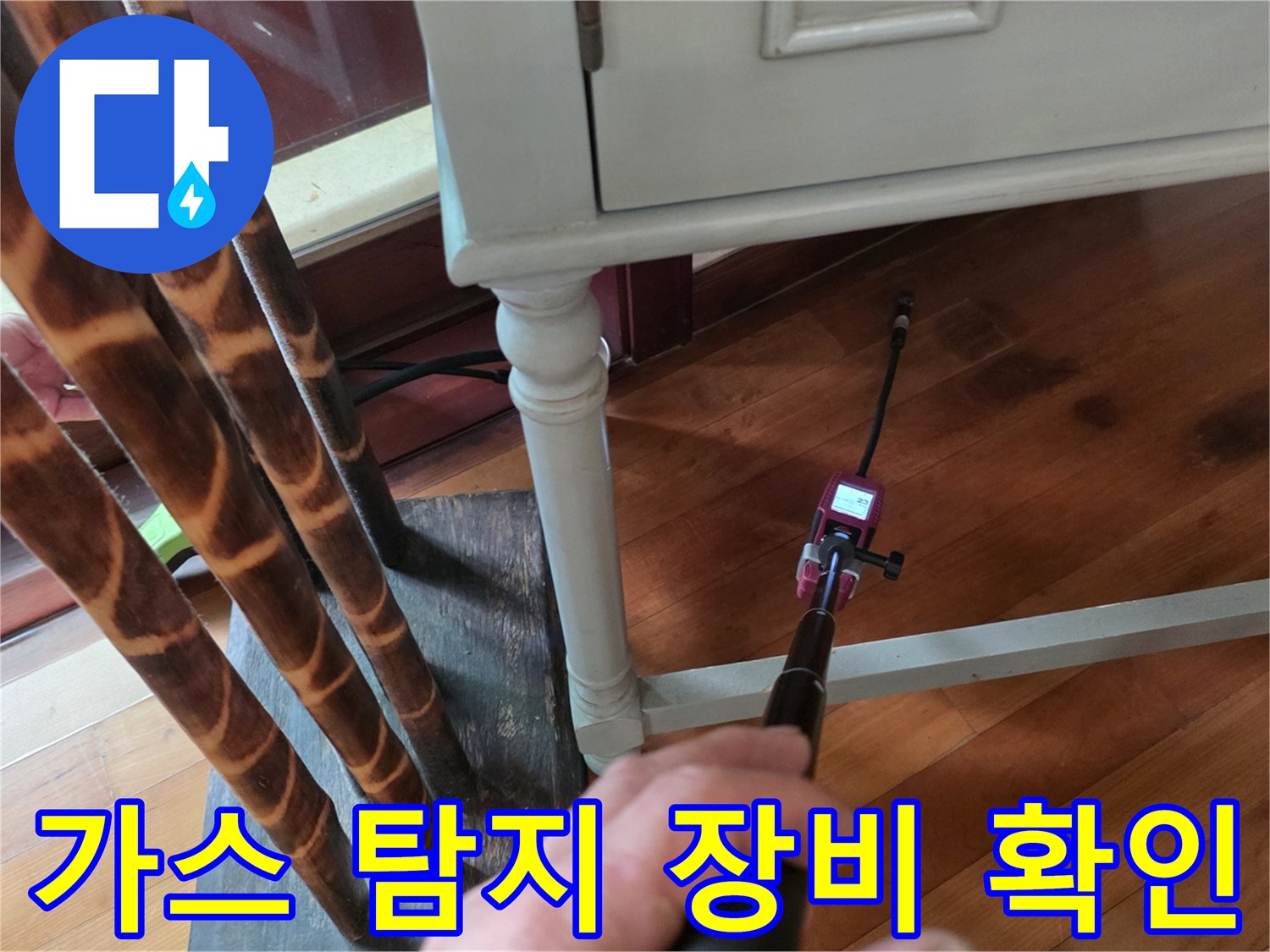 거실 마루 바닥 근처에서 가스 탐지기를 사용하여 누수 지점을 추적하는 모습