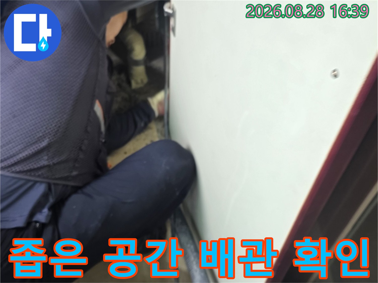 싱크대 아래 좁은 틈새를 통해 노출된 배관들을 점검하고 있습니다.