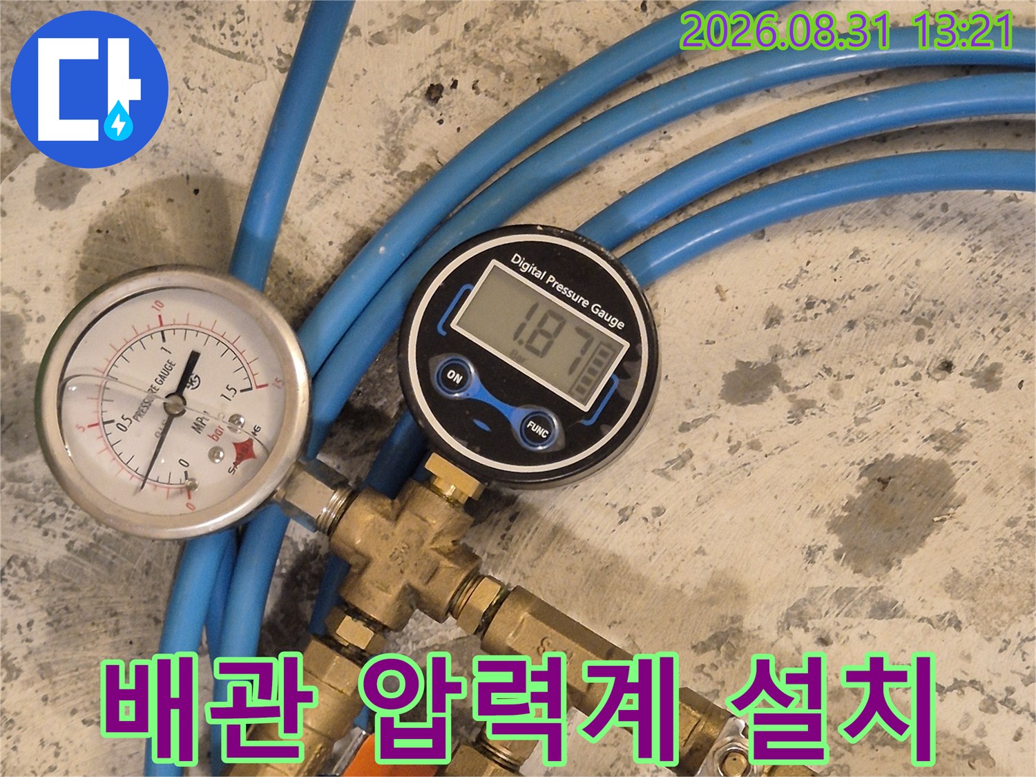 파란색 호스와 금속 부품으로 연결된 배관 압력 측정 시스템입니다.