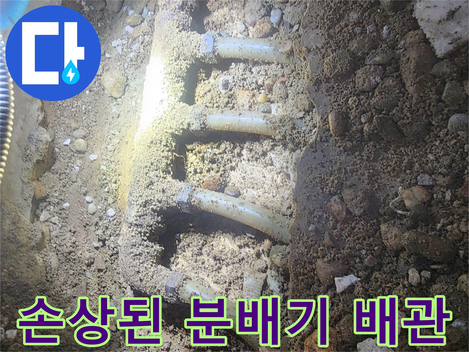 흙과 자갈 사이에 노출된 부식된 금철제 분배기 연결 부위