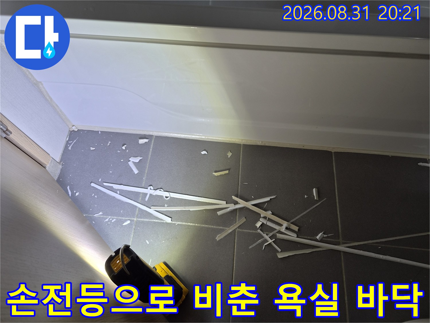 어두운 욕조 밑 공간을 손전등으로 집중 조명하여 점검하는 모습