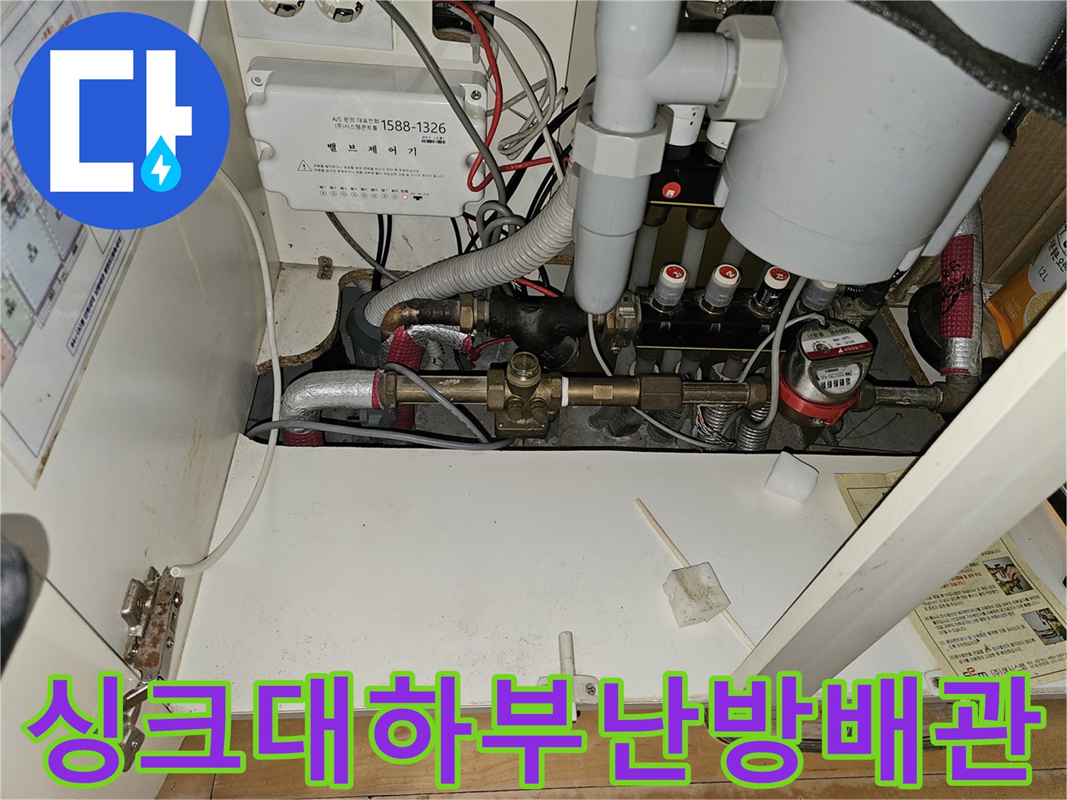 분당 백현동 아파트 싱크대 하부장에 설치된 노후된 난방 분배기와 금속 배관 모습입니다.