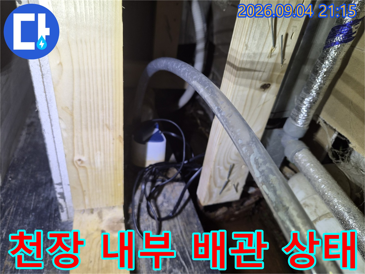 상가 천장 목재 구조물과 그 사이를 통과하는 에어컨 배수 호스 점검