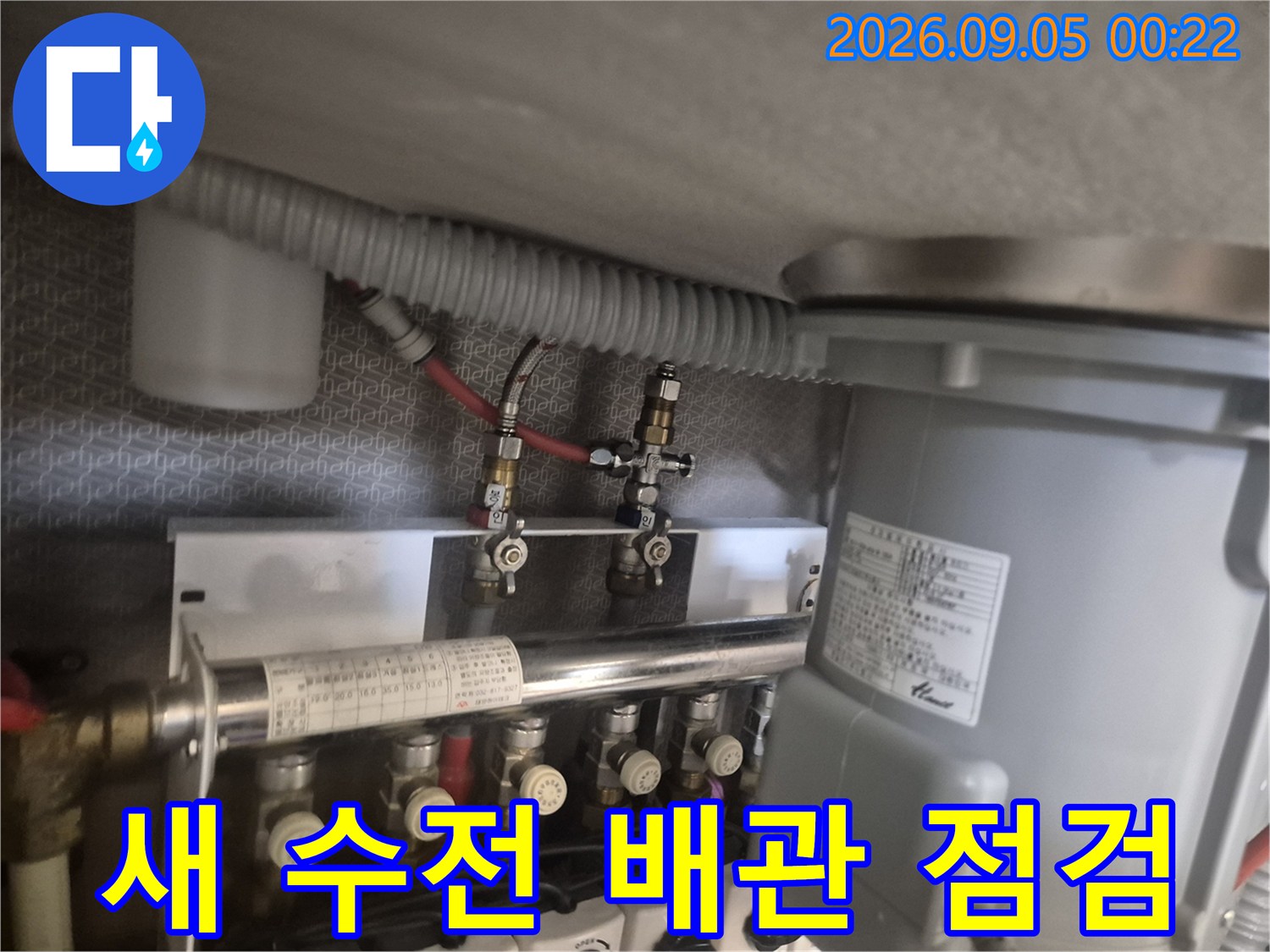 싱크대 하단 급수 밸브와 연결된 호스들의 체결 상태를 확인하는 장면입니다.