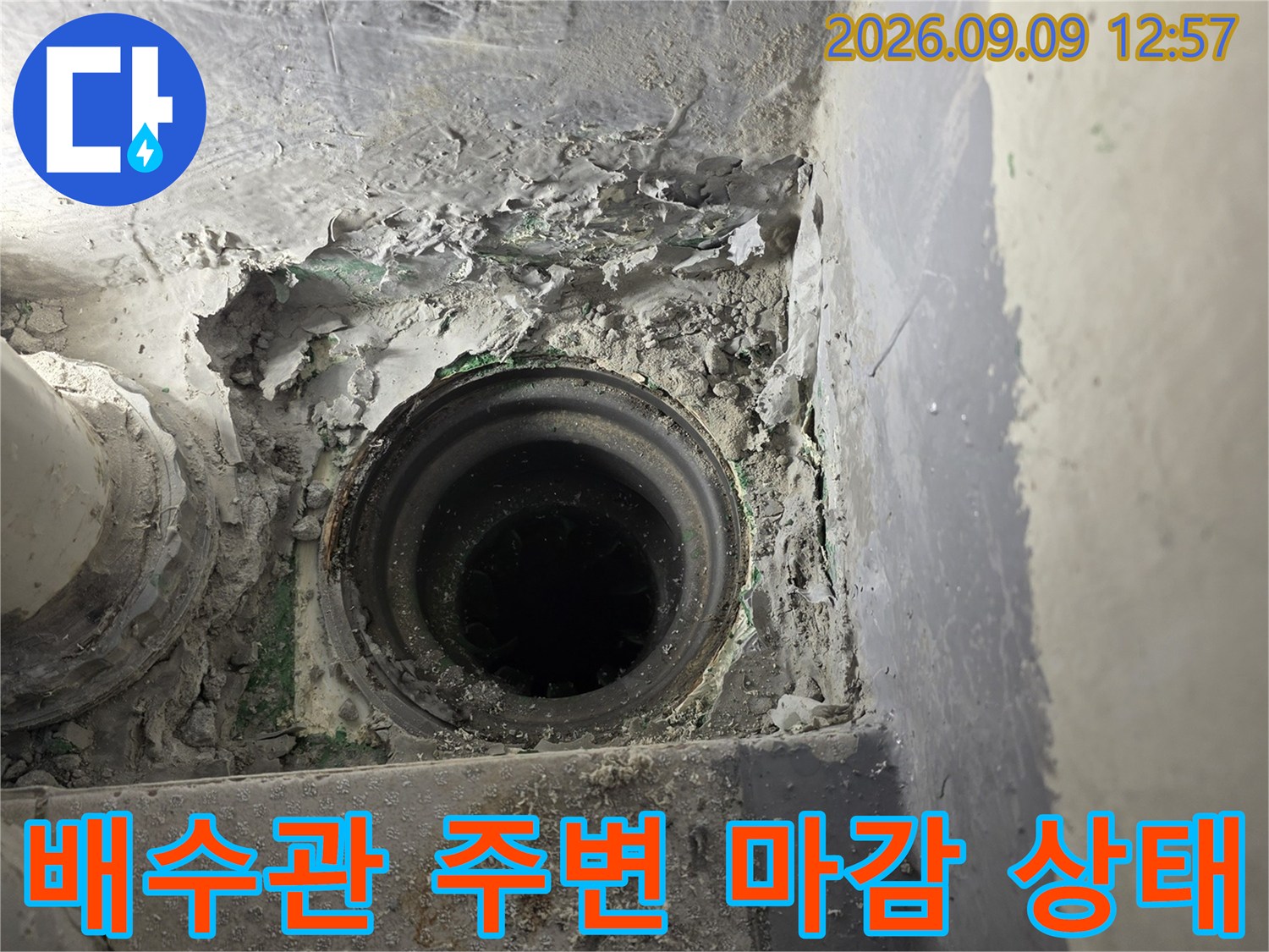 누수가 발생하는 배수관의 연결 부위와 깨진 마감재를 보여줍니다.