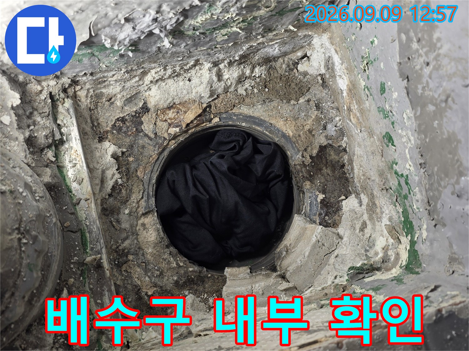 배수관 주변의 깨진 시멘트와 노출된 배관 입구