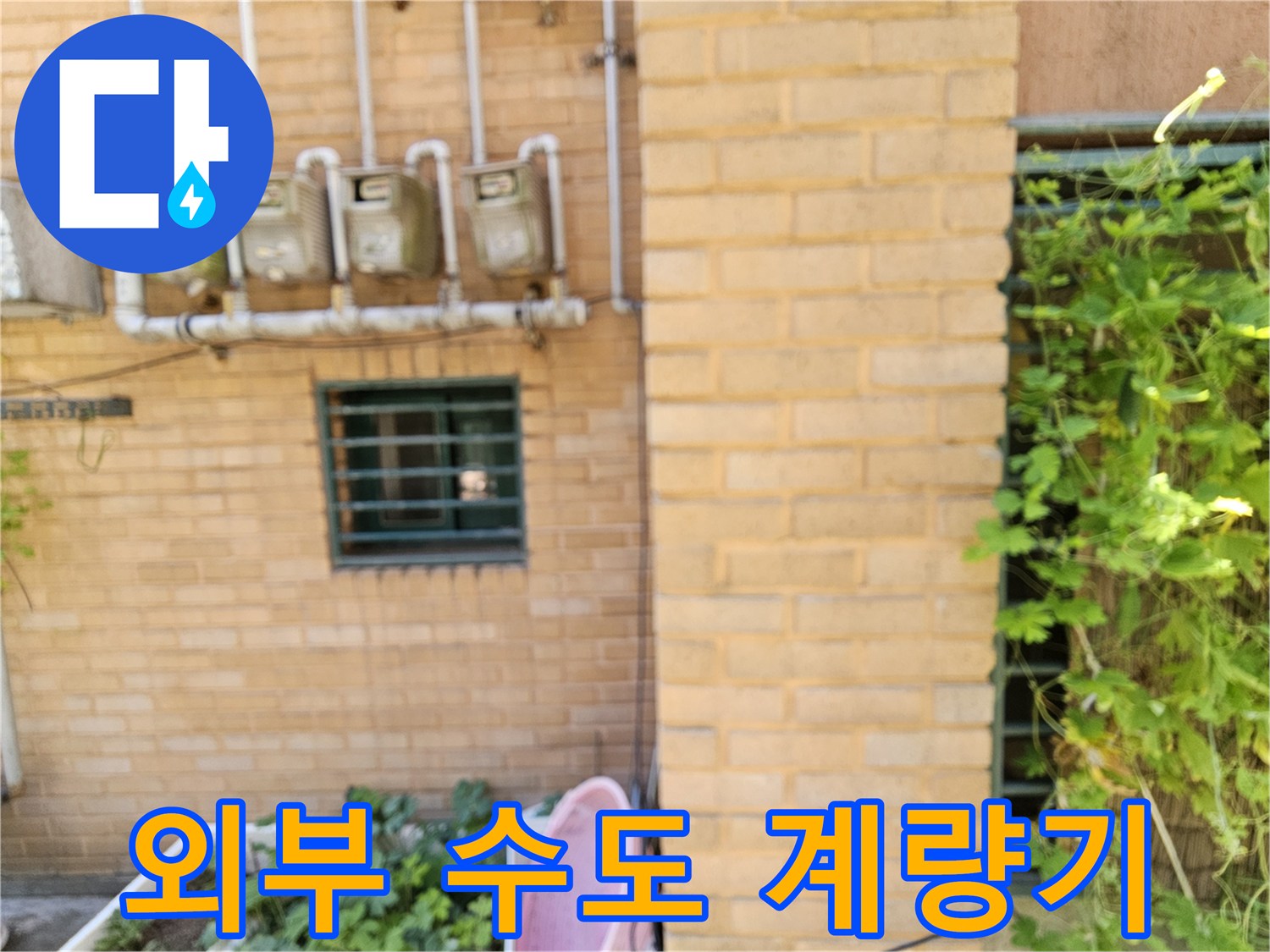 빌라 외벽 벽돌 사이에 설치된 수도 계량기와 배관들
