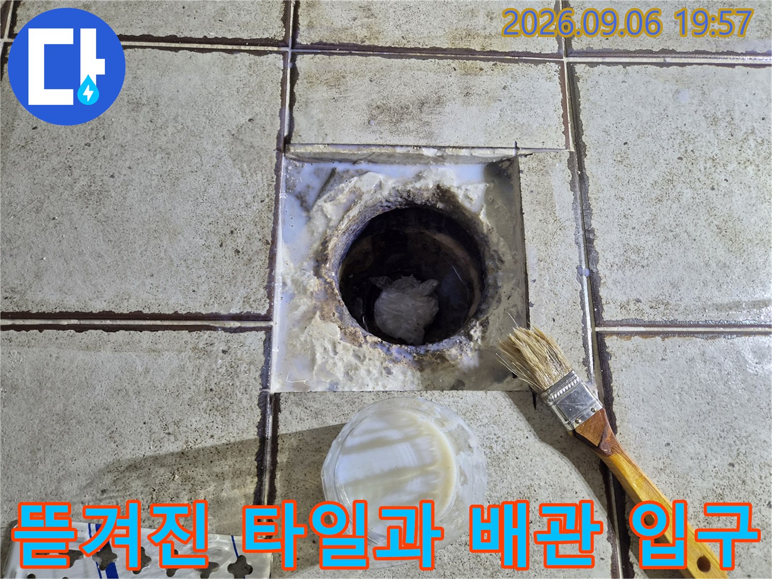 배수구 주변의 훼손된 타일면과 내부 배관이 드러난 현장 사진입니다.
