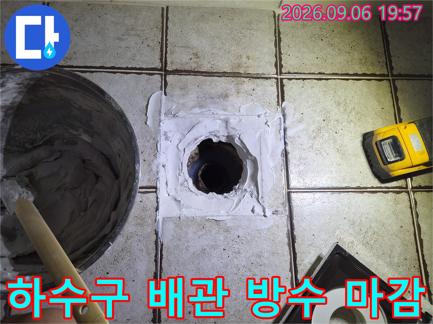 하수구 배관 주변의 틈새를 하얀 실란트로 메워 물이 새지 않게 작업하고 있습니다.