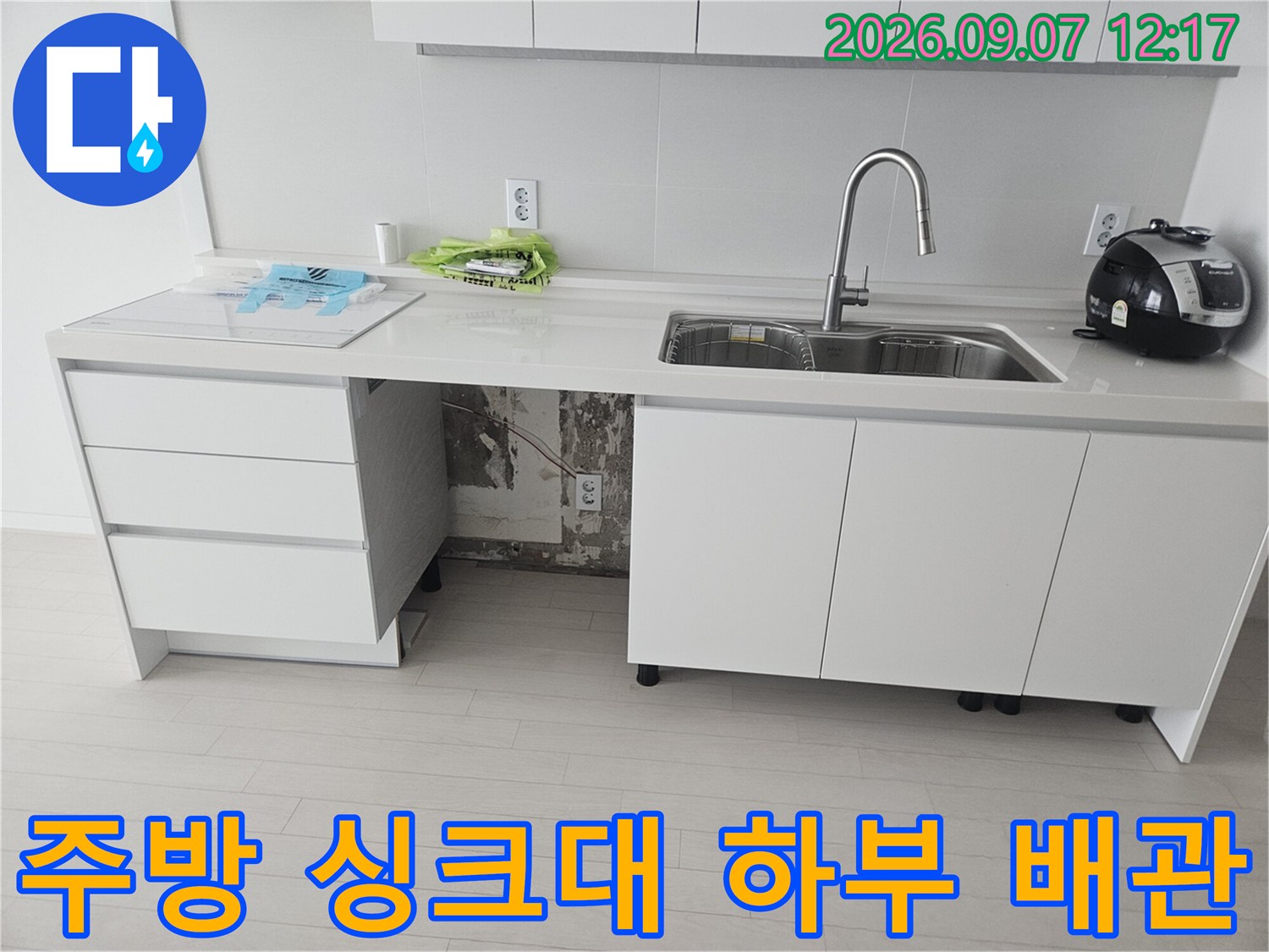 싱크대 아래쪽의 훼손된 호스 연결 부위와 배관 구조를 보여줍니다.