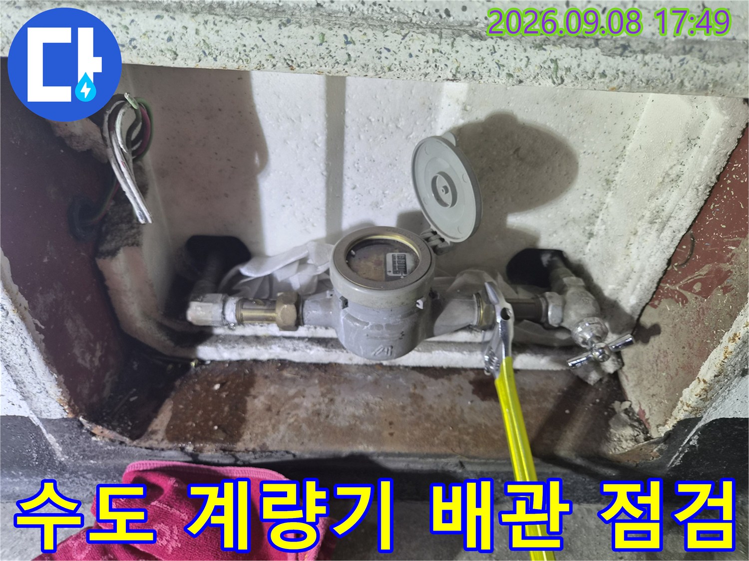 금속제 배관 부품과 수도 계량기가 설치된 내부 모습입니다.