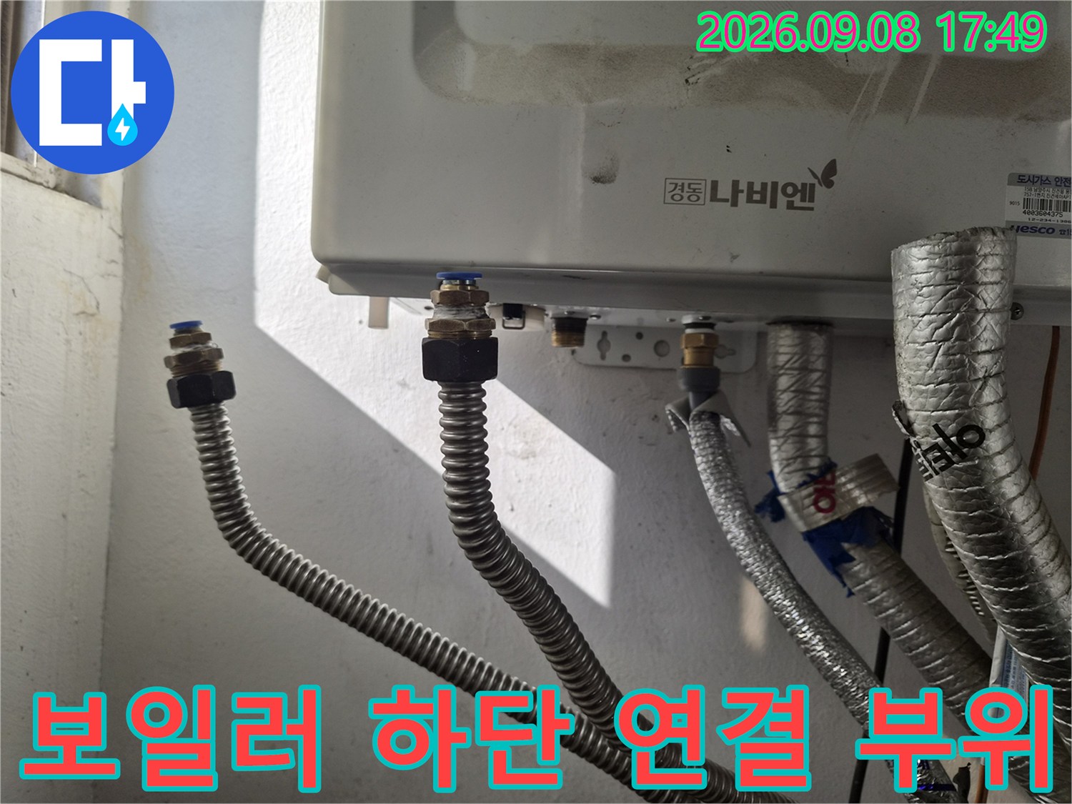 보일러 하단-금속 어댑터와 은색 주름관의 상세 모습