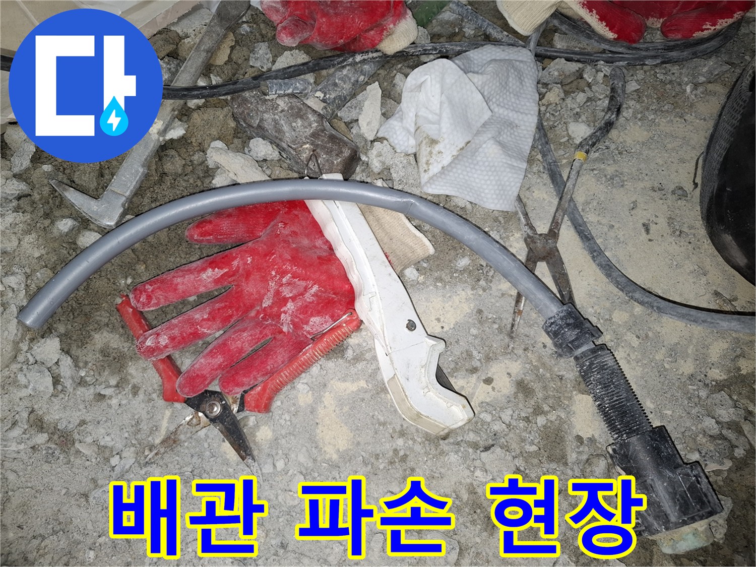 파손된 회색 배관과 작업용 장갑이 놓인 현장