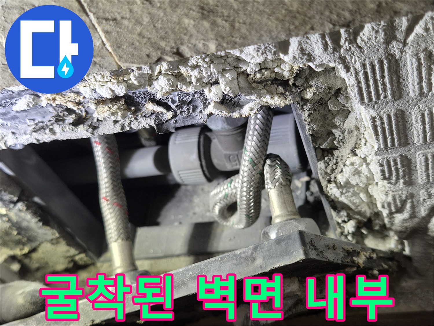 콘크리트 굴착 부위와 노출된 금속 배관의 근접 촬영