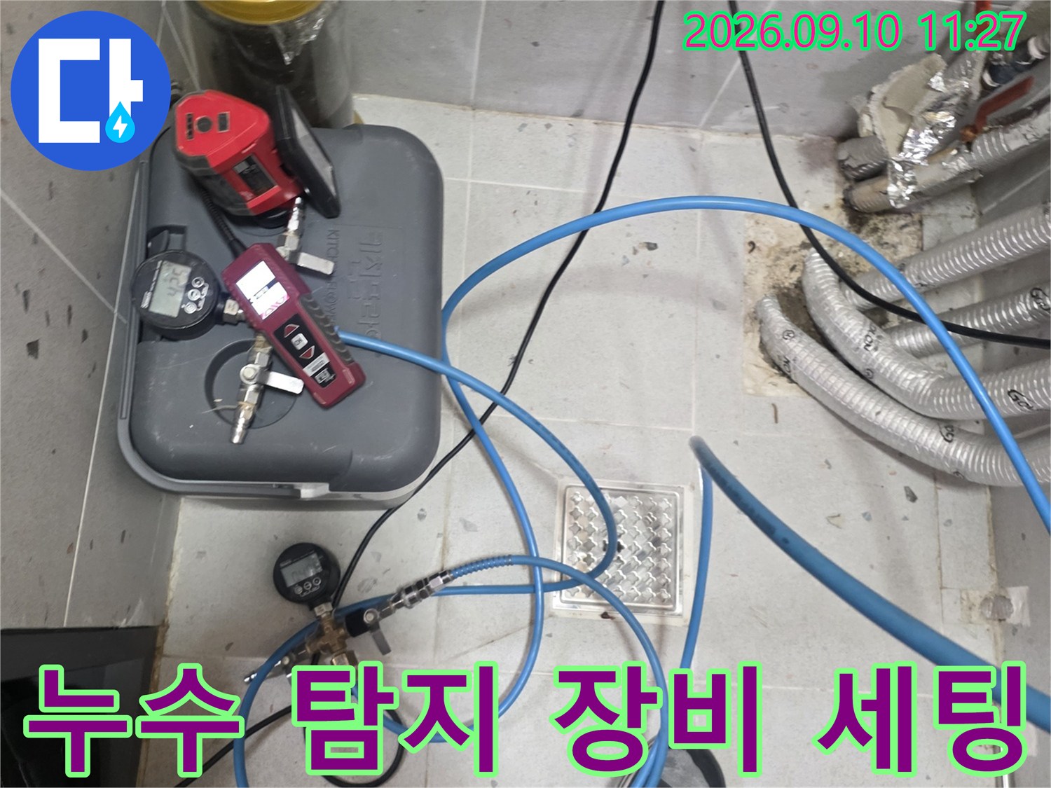 누수 지점을 찾기 위해 배관에 연결된 압력 측정 장비와 호스들