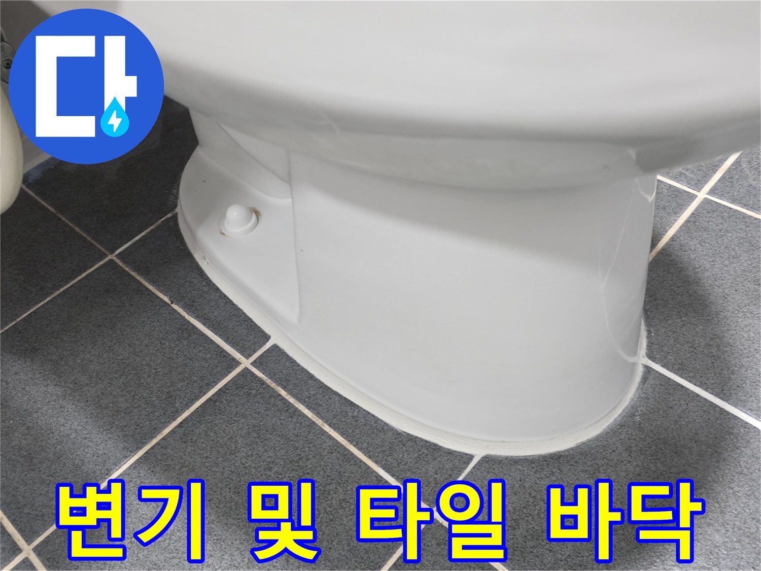 변기와 어두운색 욕실 타일의 경계 부위입니다.