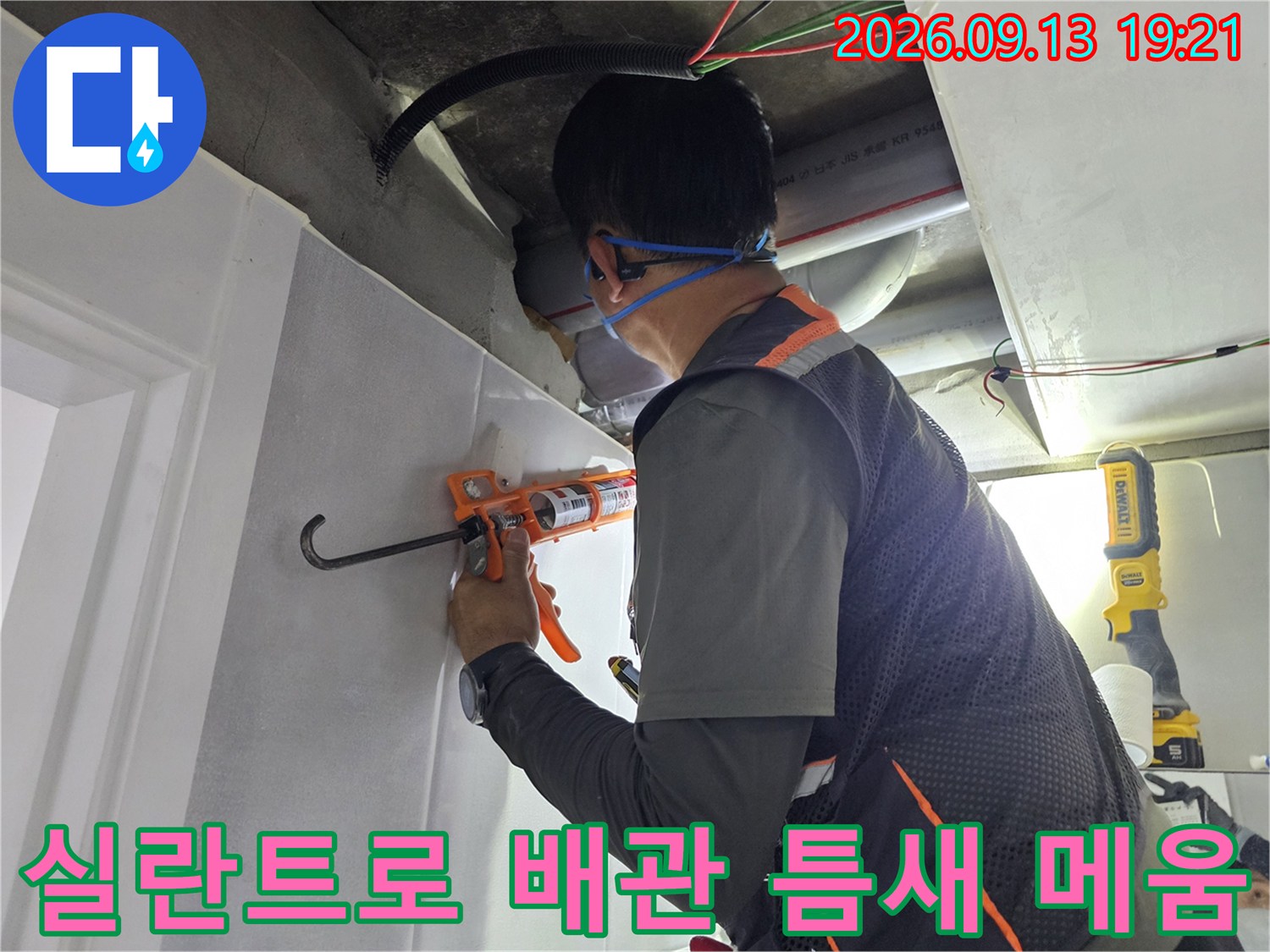 작업자가 실란트 건을 사용하여-배관의 누수 지점을 밀봉하고 있습니다