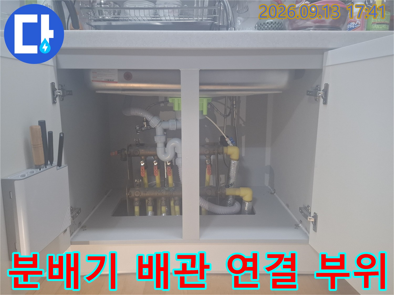 싱크대 하부장에 노출된 보일러 분배기와 노란색 PE-RT 배관들