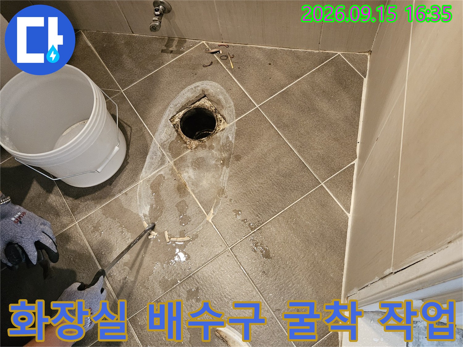 욕실 바닥 공사-노출된 배관과 주변에 떨어진 타일 조각들