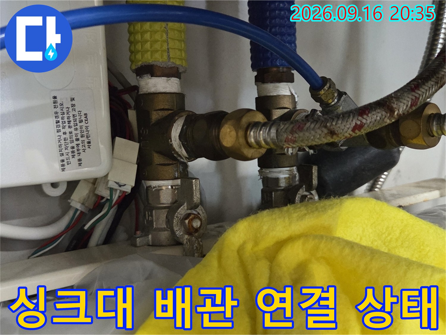 금속 부품과 호스가 복잡하게 연결된 싱크대 하단 모습입니다.