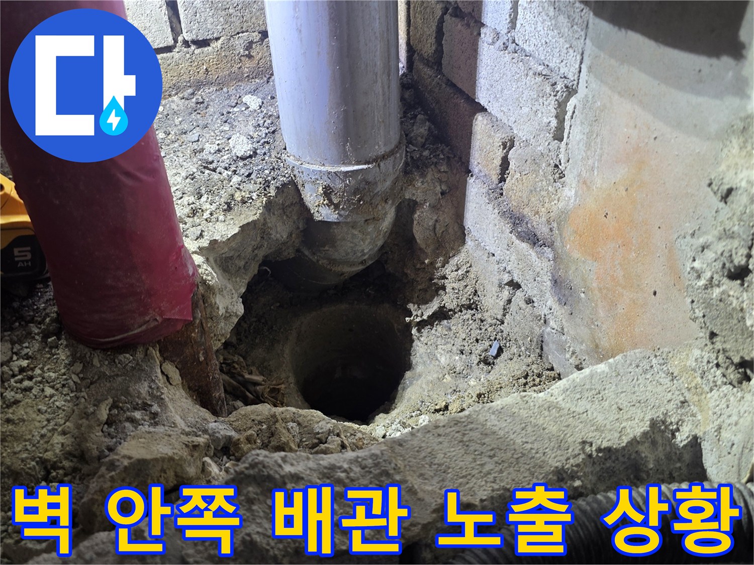 벽면을 뚫고 드러난 하얀색 관과 주변의 굴착된 잔해물입니다.
