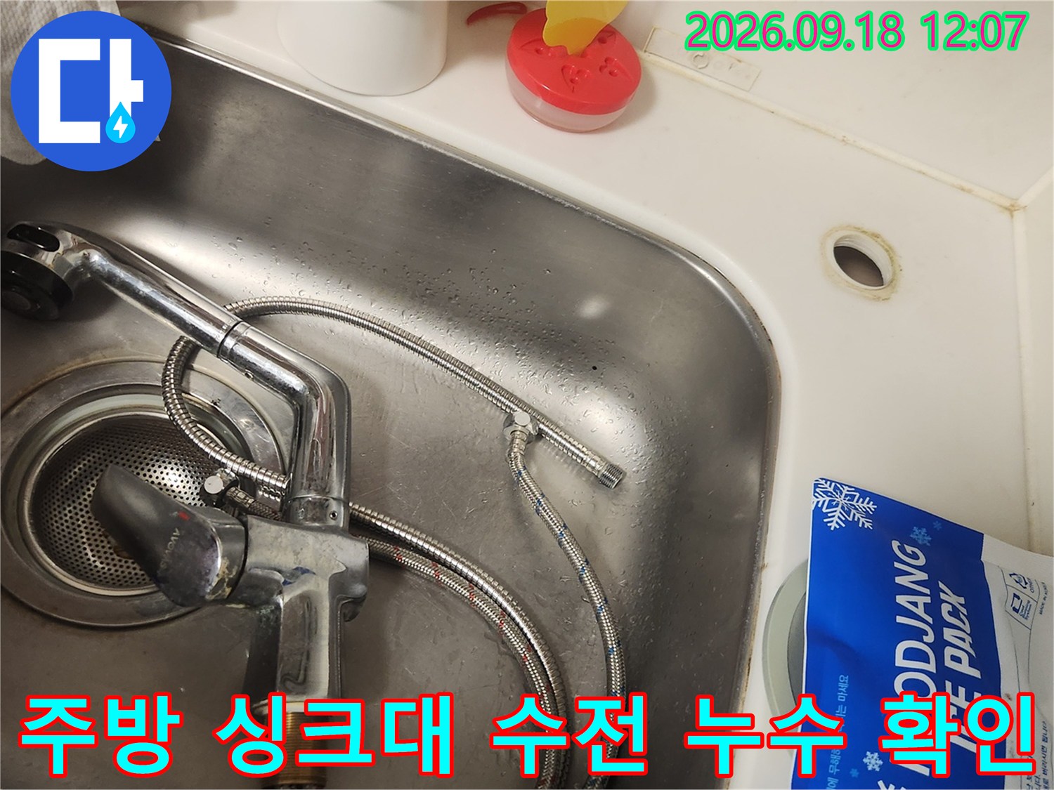 스테인리스 싱크볼에 부착된 수전의 연결 호스 부근을 점검하고 있습니다.
